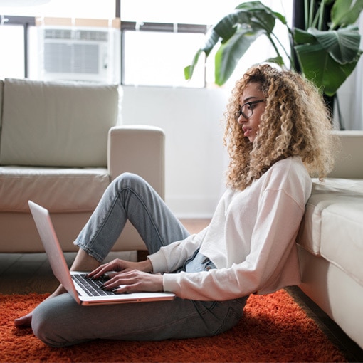 Woman sitting on floor using laptop.